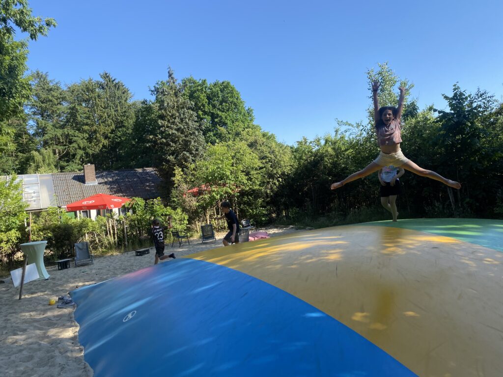 Kinder springen auf einem großem Hüpfkissen